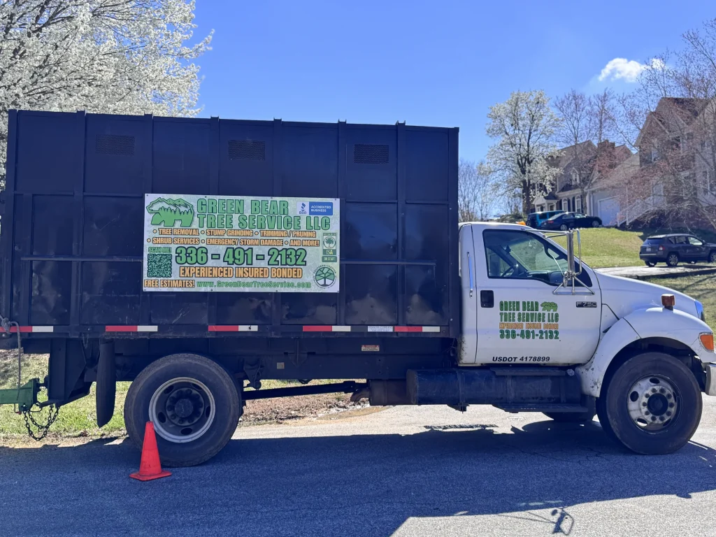 Green Bear Tree Service chipper body truck parked in residential neighborhood with flowering trees NC